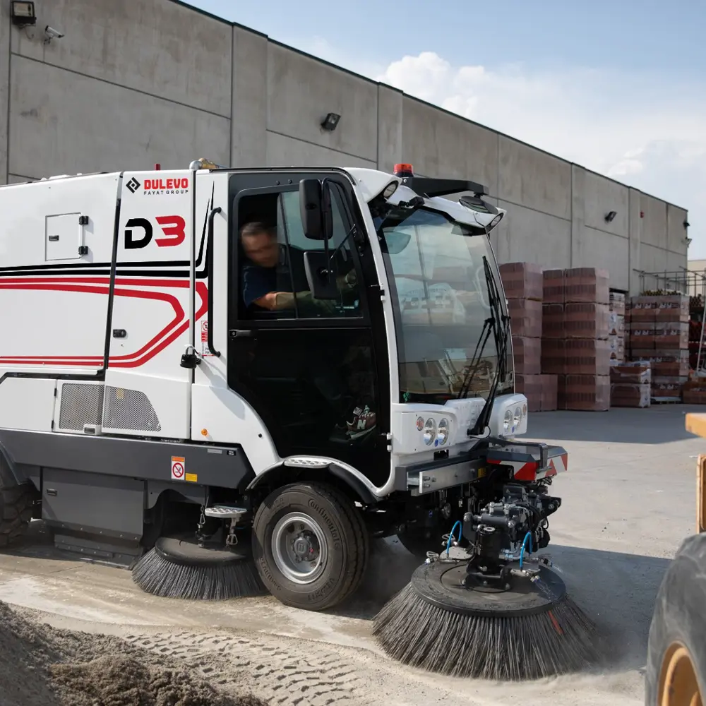Dulevo D3 straatveegmachine veegt bouwterrein met bestuurder in cabine