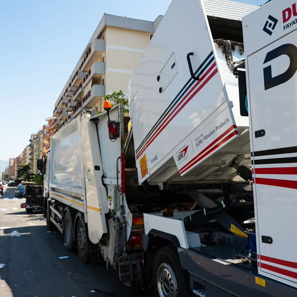 Dulevo D6 veegwagen achter een vuilniswagen in een stedelijke omgeving
