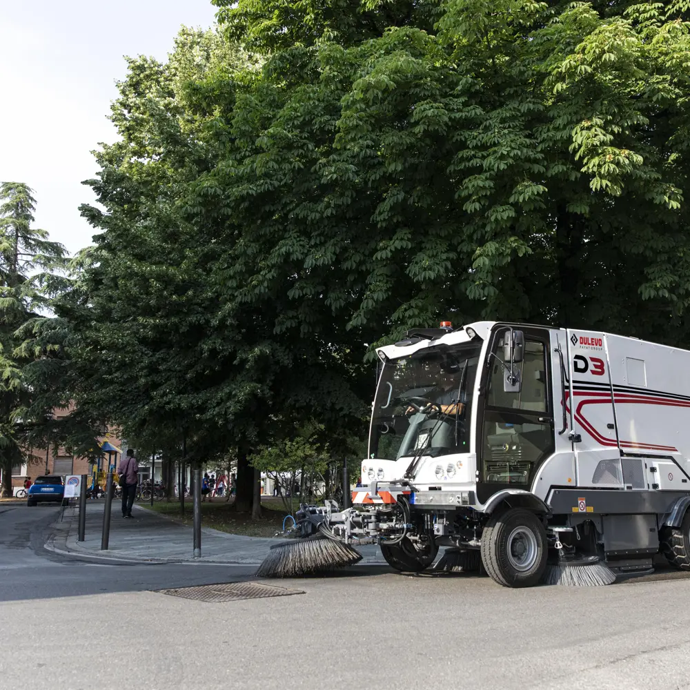 Dulevo D3 veegmachine reinigt stadsplein onder groene bomen in centrum