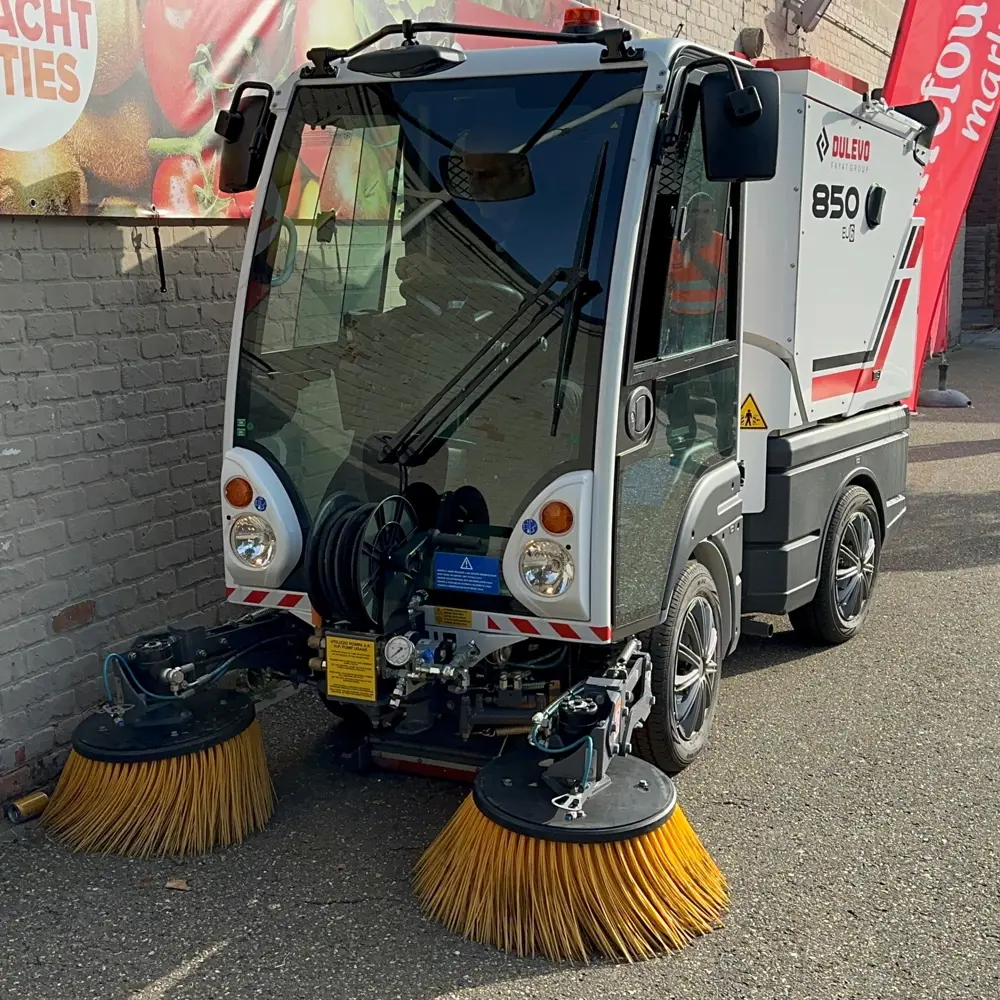 Compacte Dulevo 850 straatveegmachine met gele zijborstels veegt straat in België