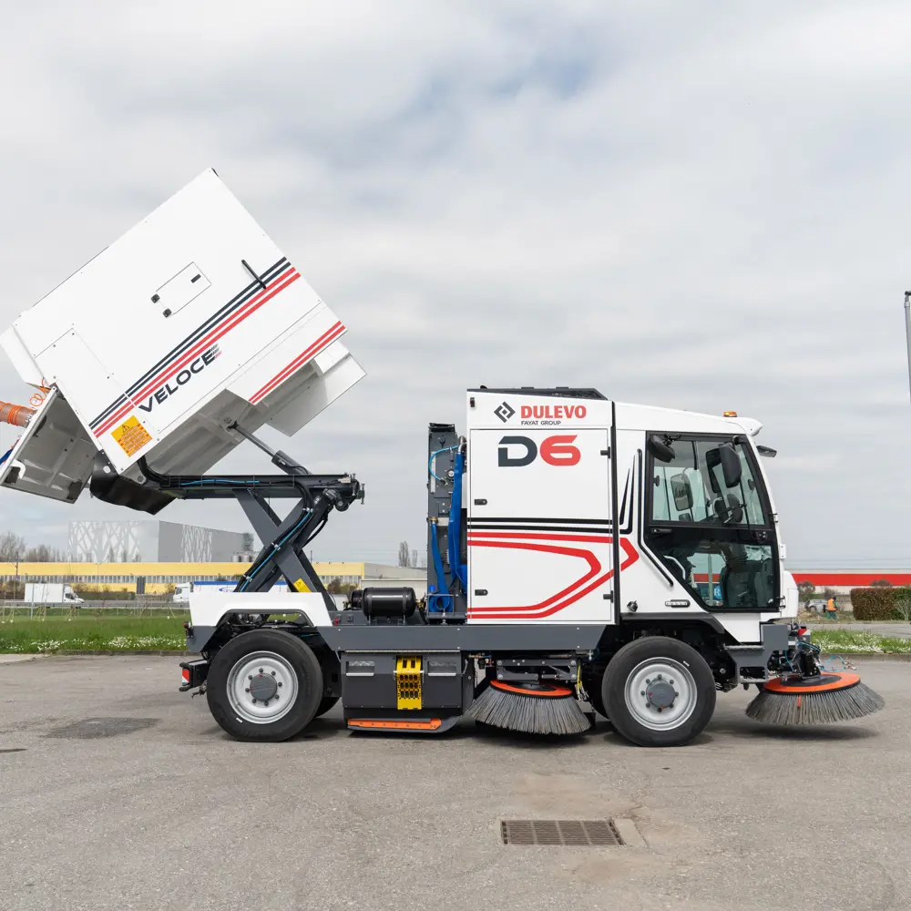 Dulevo D6 Veloce met geheven vuilcontainer voor lossing, zijaanzicht op bedrijfsterrein