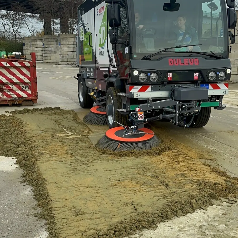 Dulevo D6 Veloce veegwagen veegt zand op een industrieterrein met draaiende borstel