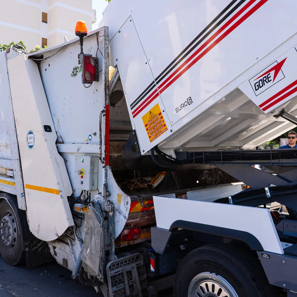 Dulevo D6 straatveegmachine leegt de container bij een vuilniswagen