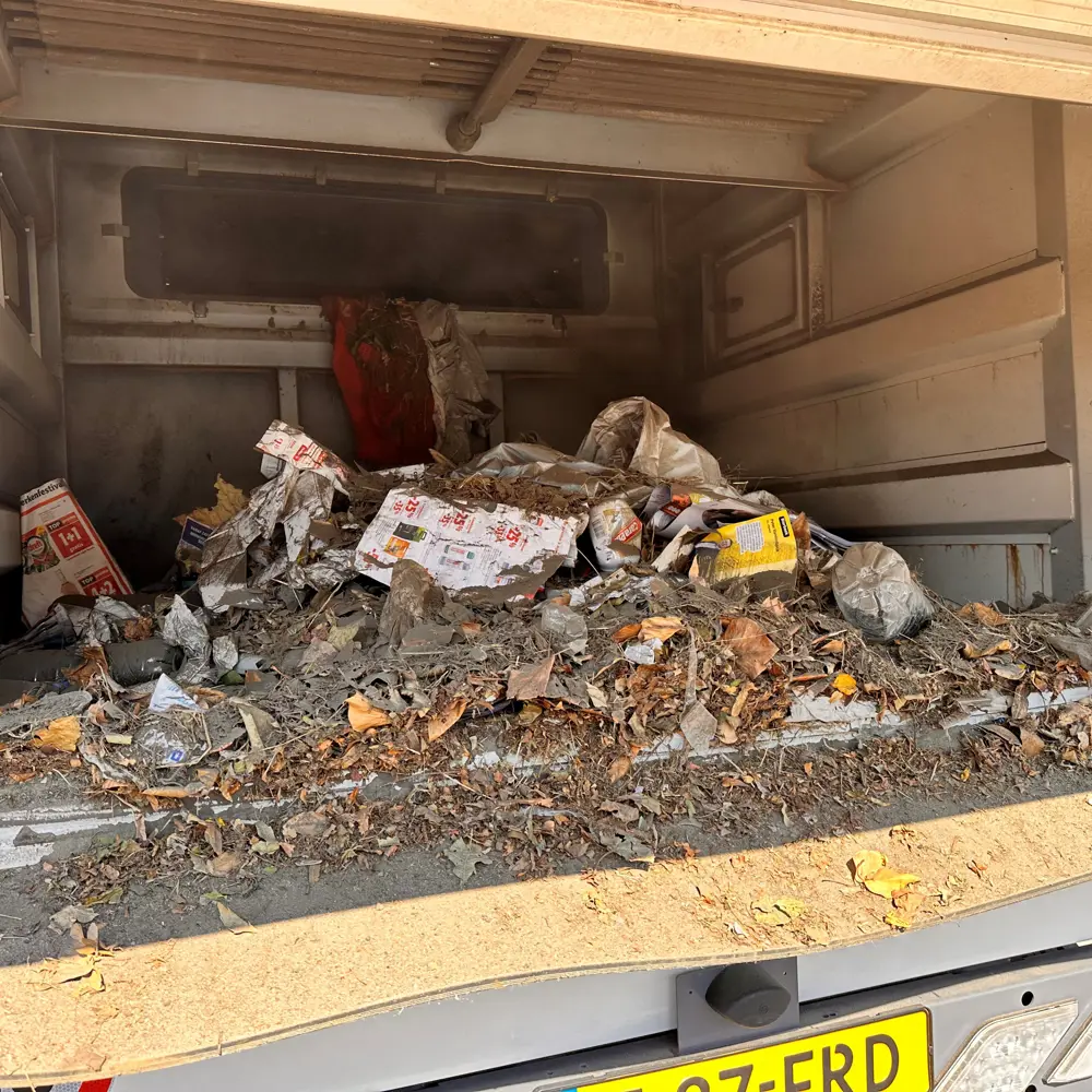 Geopende vuilcontainer van de Dulevo D6 gevuld met straatvuil en bladeren