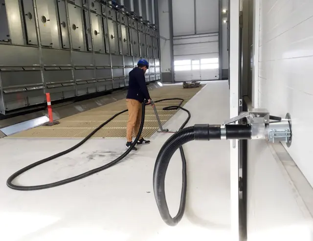 Industriele stofzuiger op leidingwerk in productiehal