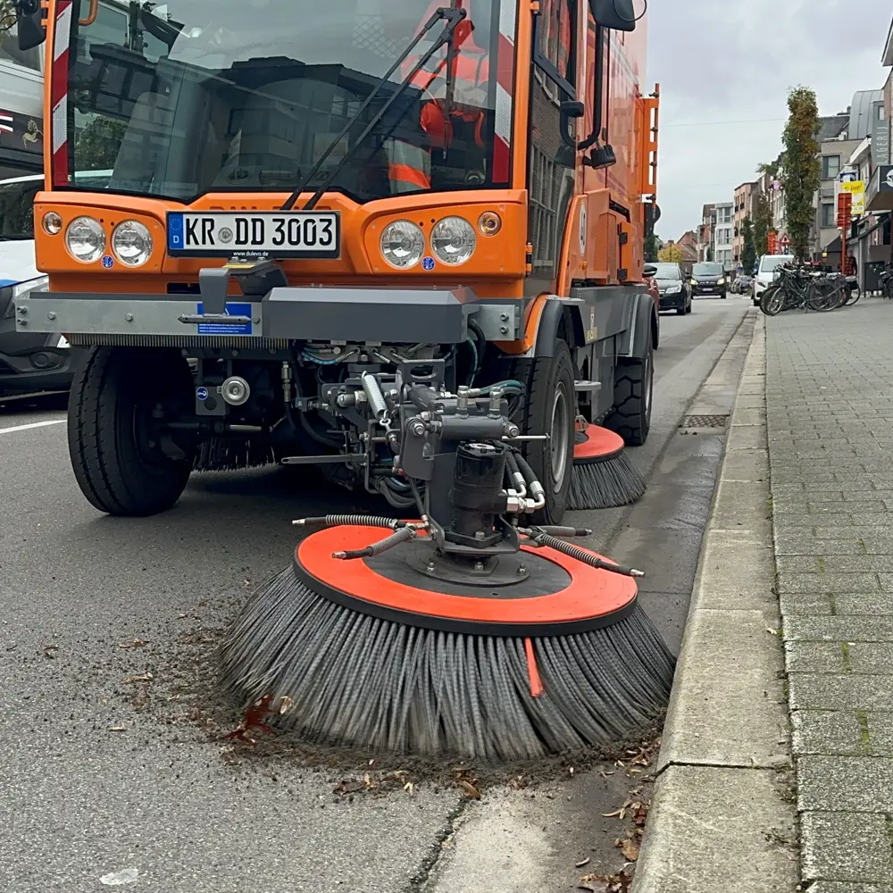 Oranje voorborstel van Dulevo veegmachine veegt bladeren langs stoeprand