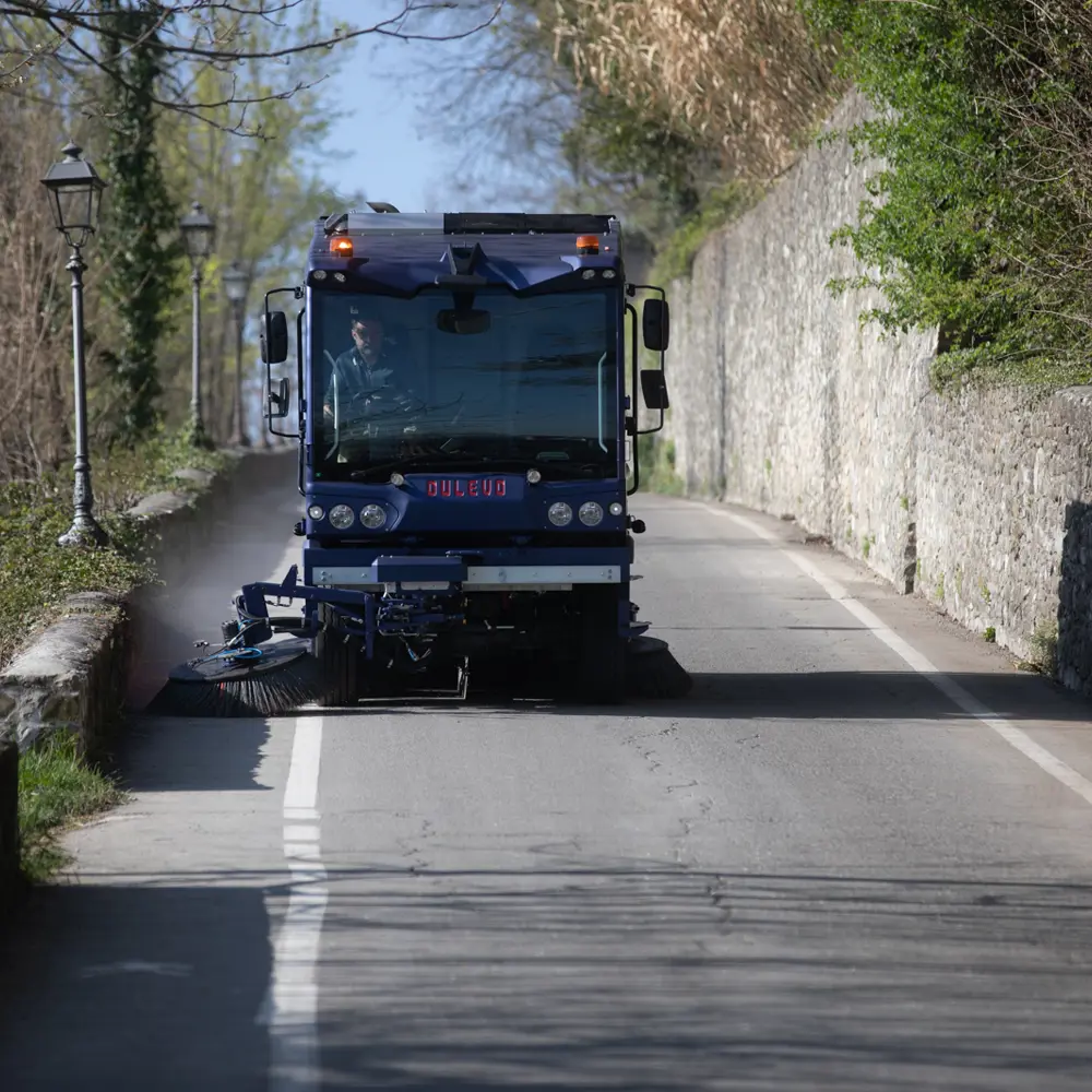 Dulevo D6 straatveegmachine op een smalle dorpsweg met stenen muren