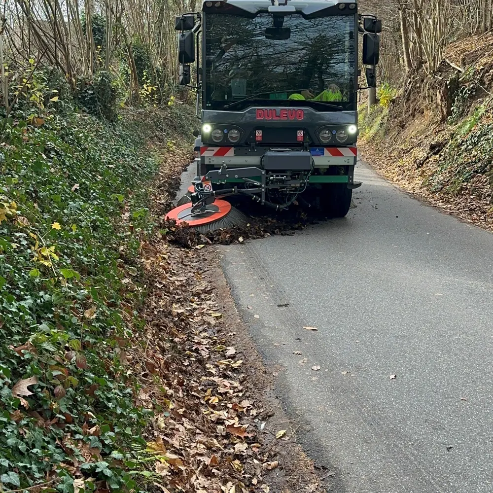 Dulevo D6 Veloce straatveegmachine veegt herfstbladeren op een smalle bosweg